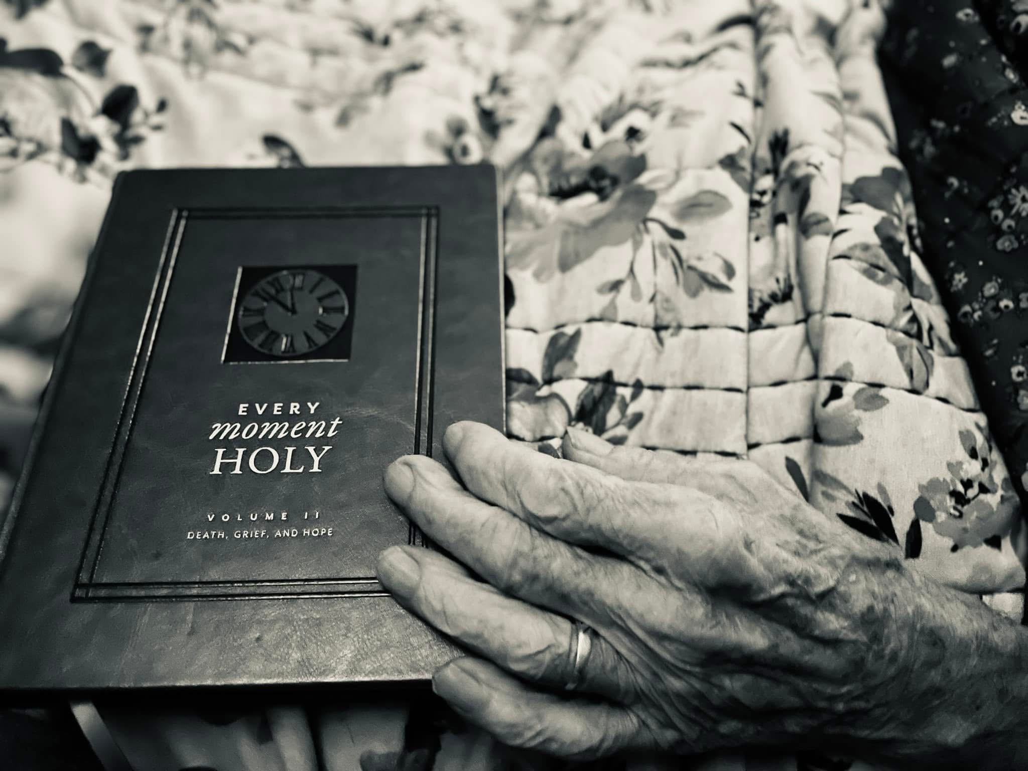 Hand holding a book on death, grief, and hope